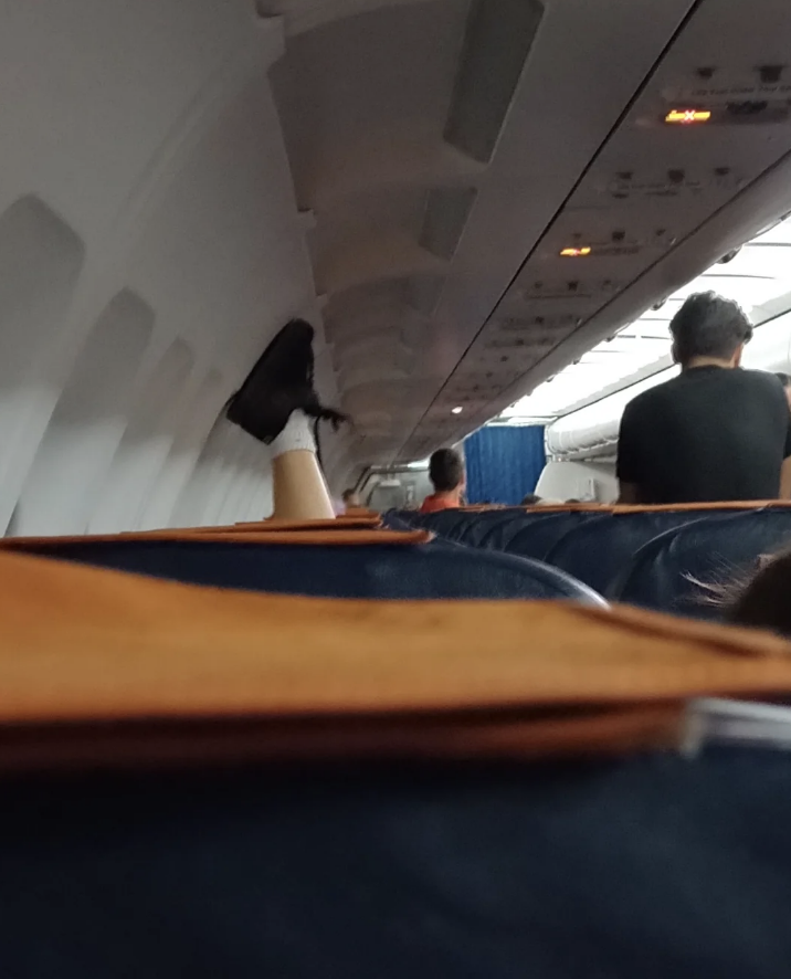 Someone is sitting upside down, with their feet on the wall of the plane above their row&#x27;s window