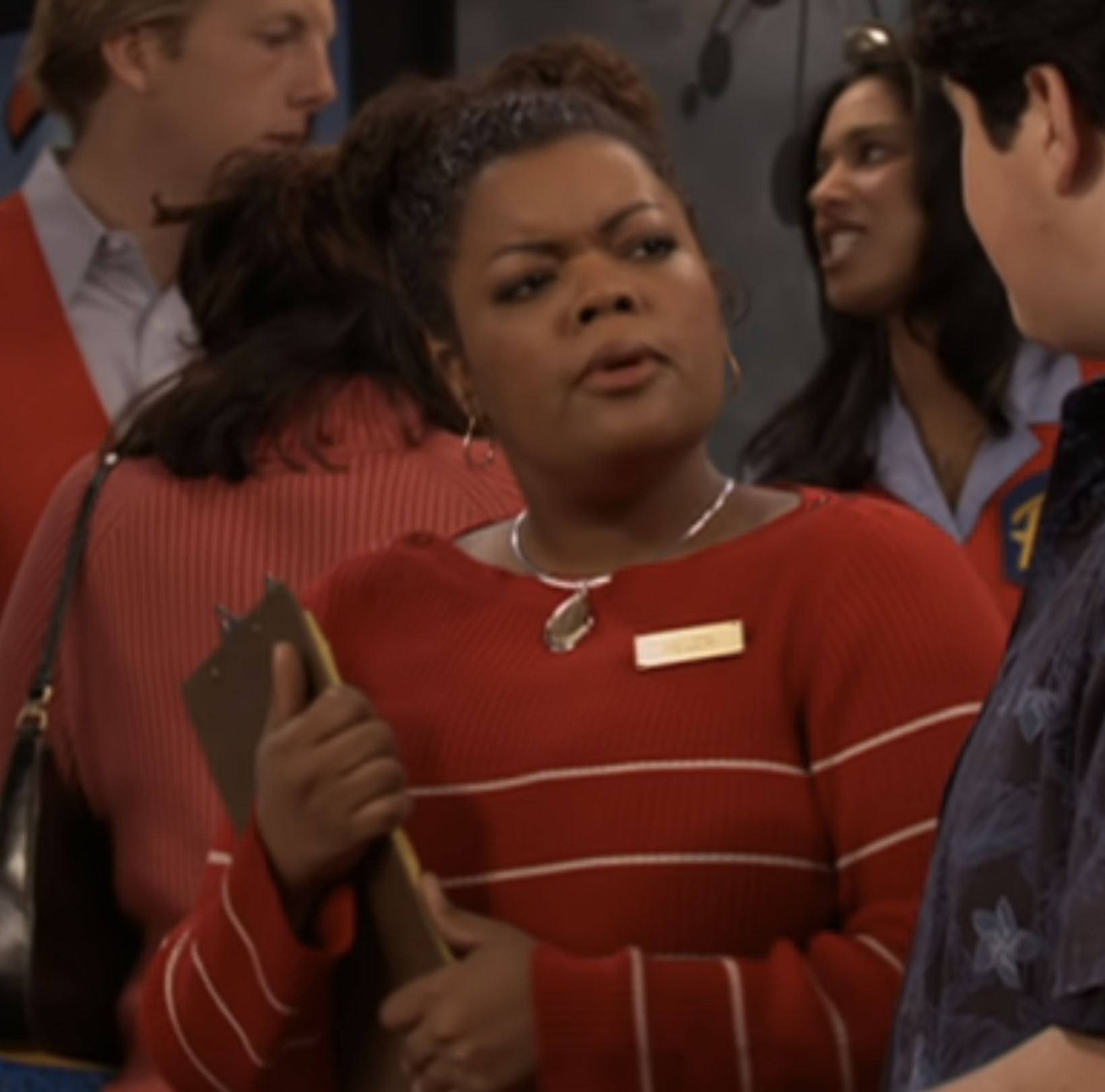 closeup of her in character holding a clipboard and wearing a name tag