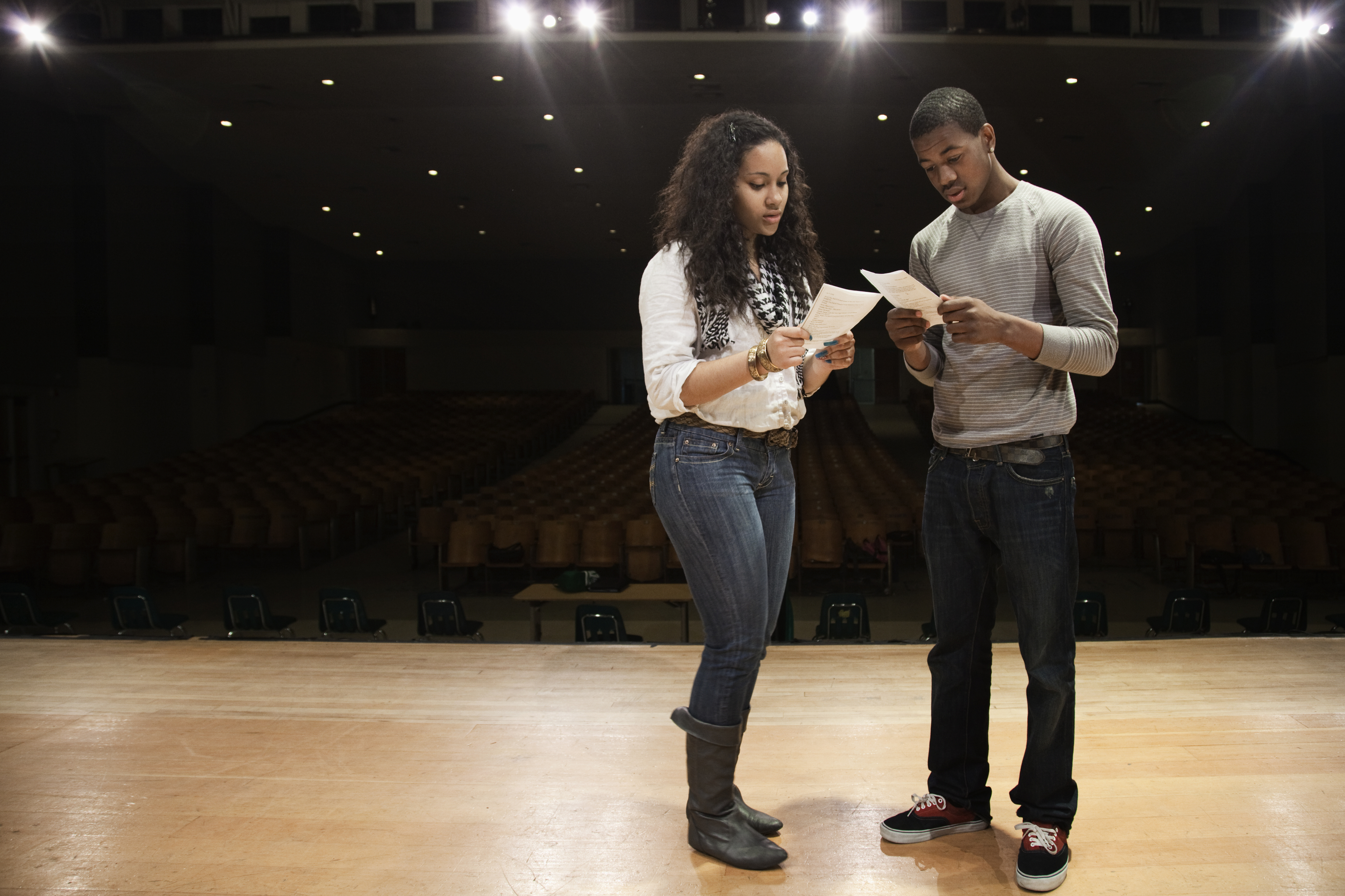 high school theater students reading a script on stage