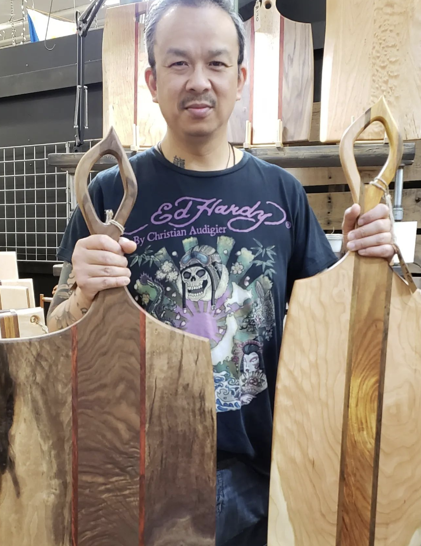 A man holds two custom-made wood cutting boards.