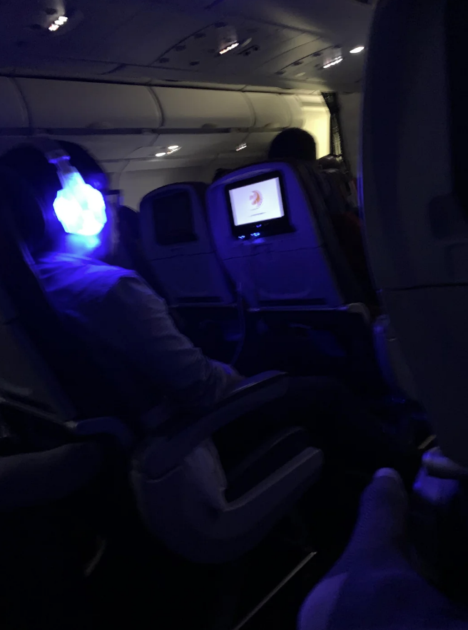 A passenger is wearing headphones that brightly glow in the dark
