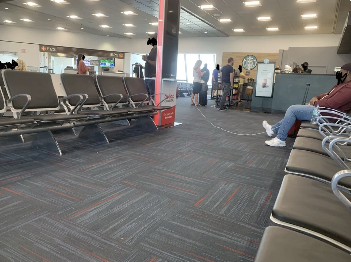 Someone has plugged their phone into an outlet, but is sitting across the aisle, so the cord extends across the entire walkway
