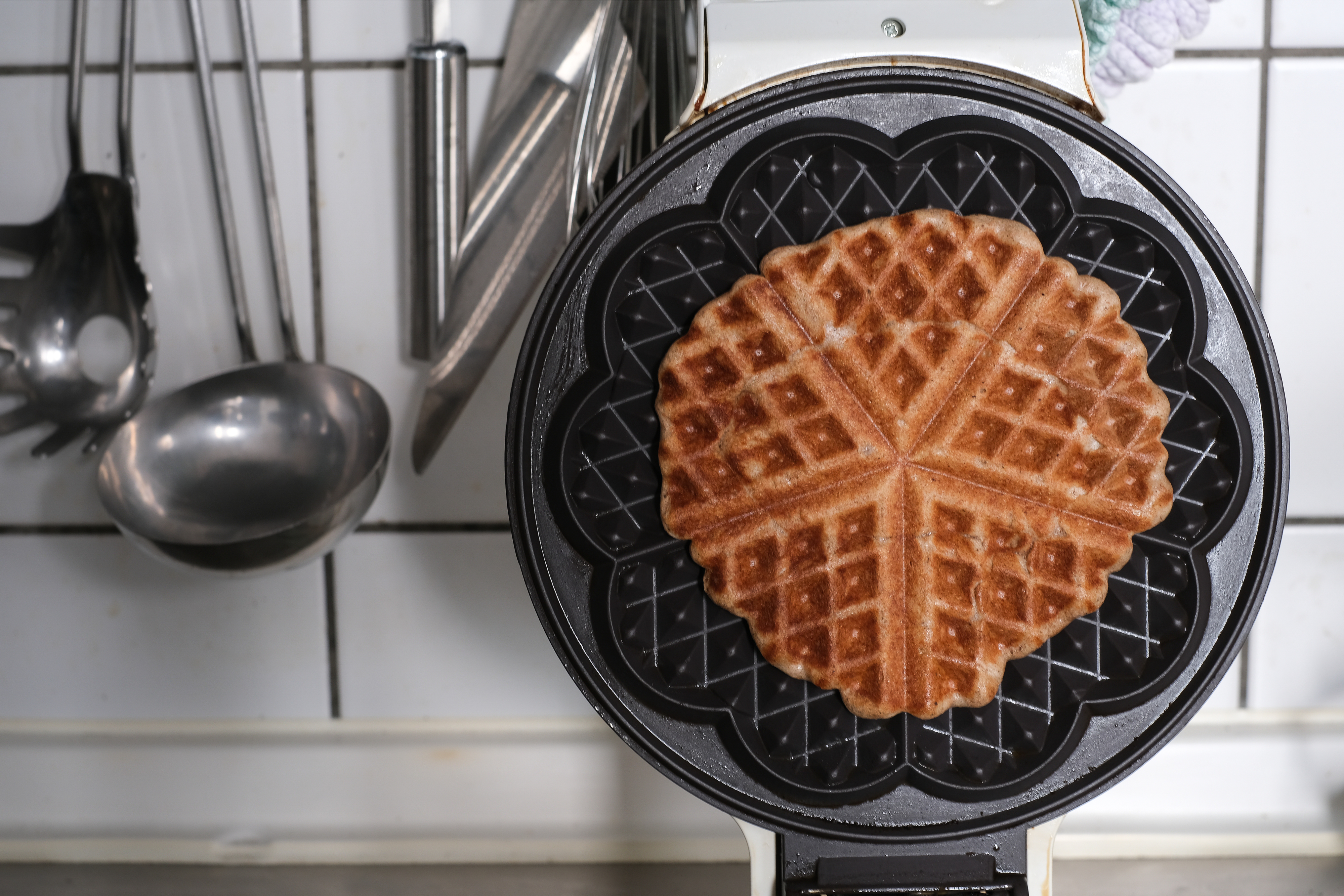 A waffle cooking in a waffle-maker