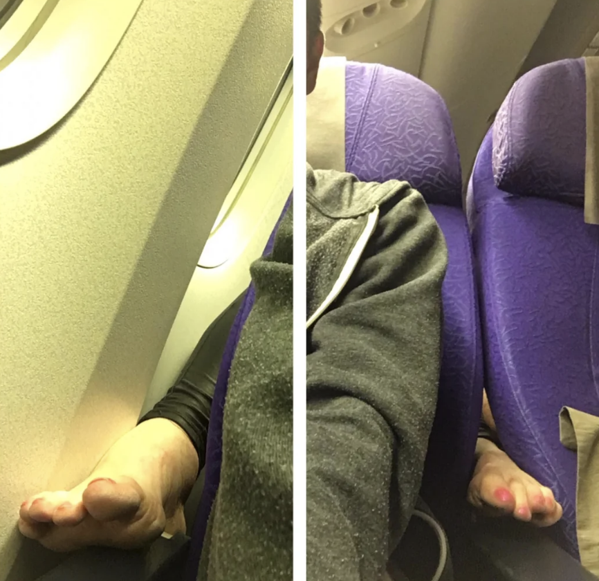 Someone&#x27;s bare feet extend on both sides of the seat, covering the arm rests