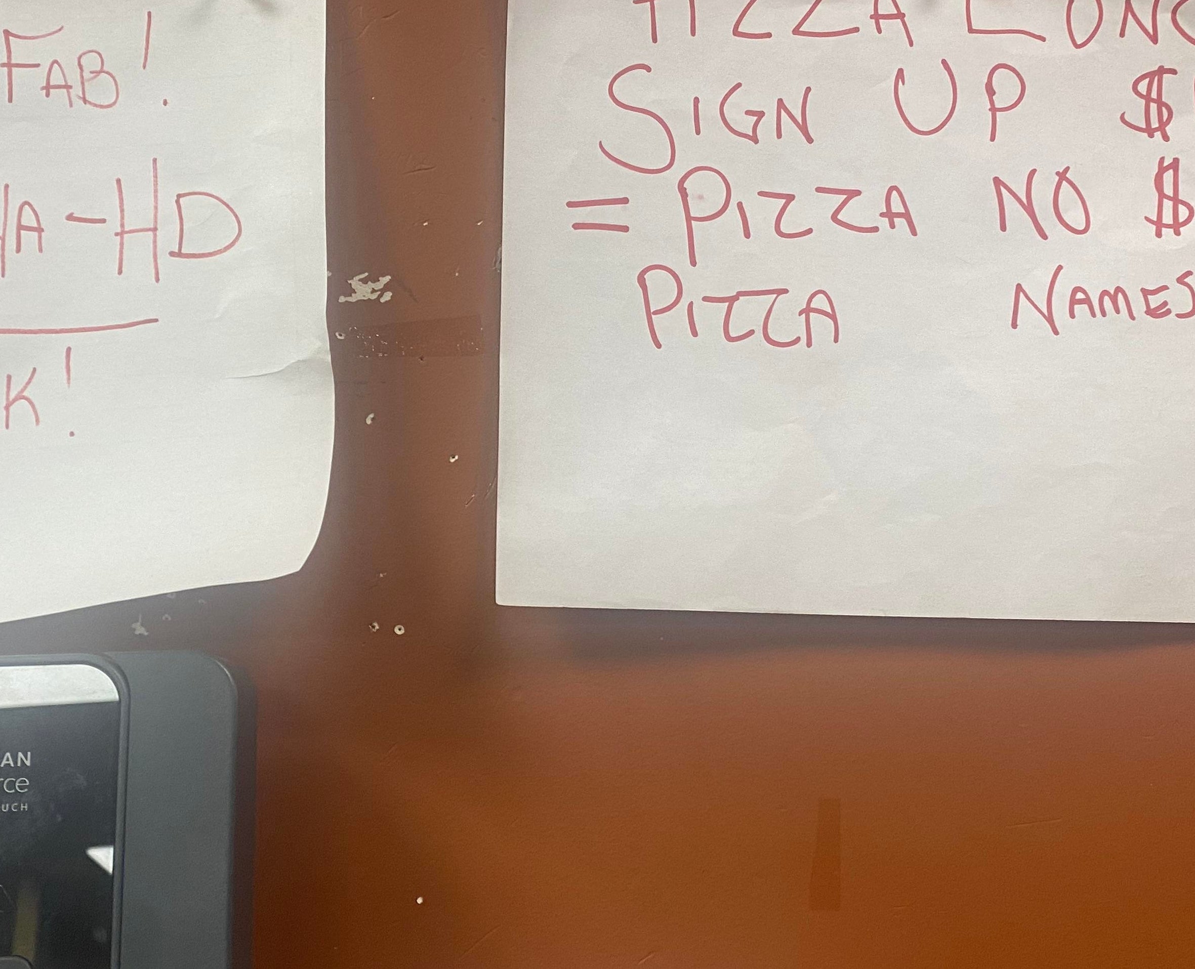A sign asks for people to sign up to pay $10 each for a pizza lunch