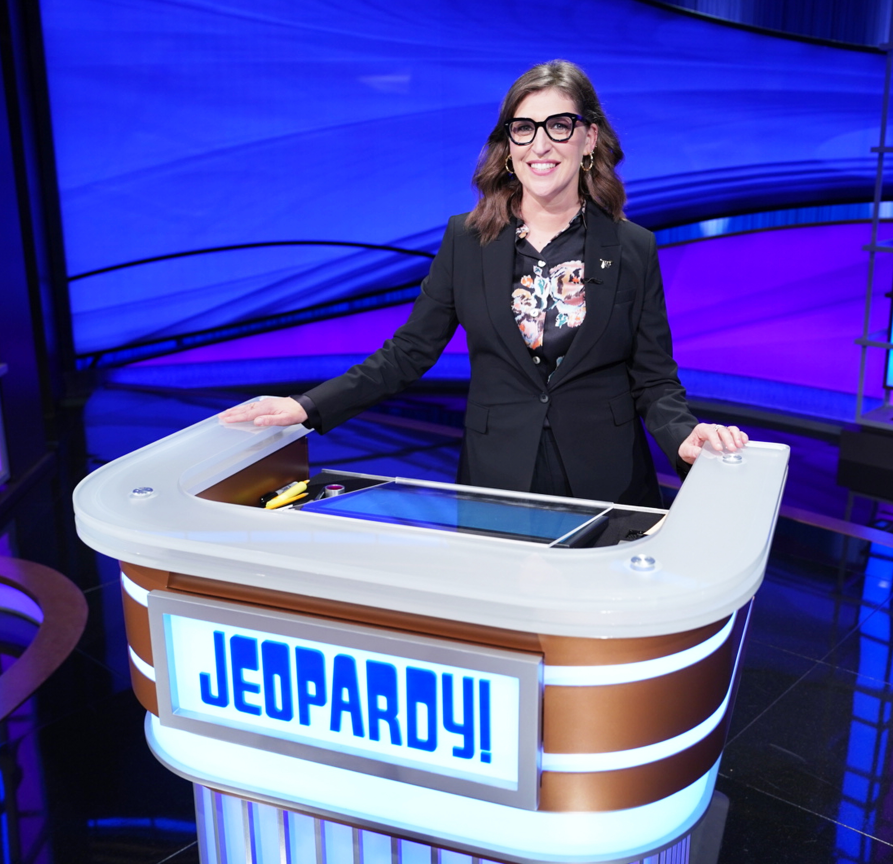 Mayim behind the jeopardy podium