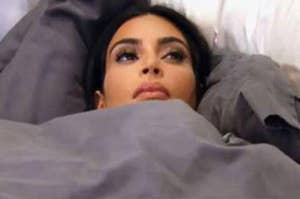 Kim Kardashian laying in bed under the covers staring off into the distance contemplating life