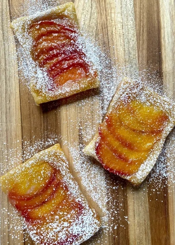 three upside down puff pastry tarts with nectarines and powdered sugar