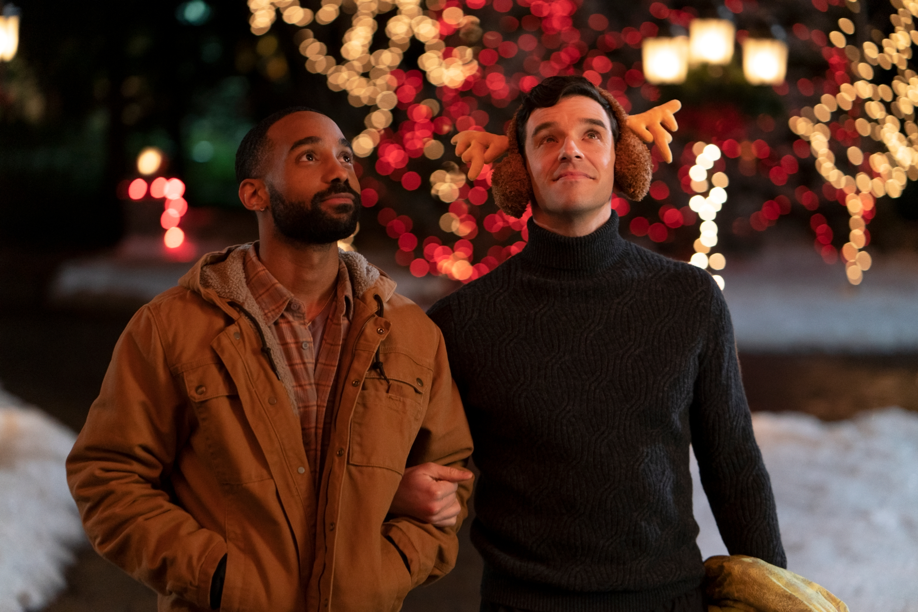 michael urie and philemon chambers linking arms and looking up at christmas lights