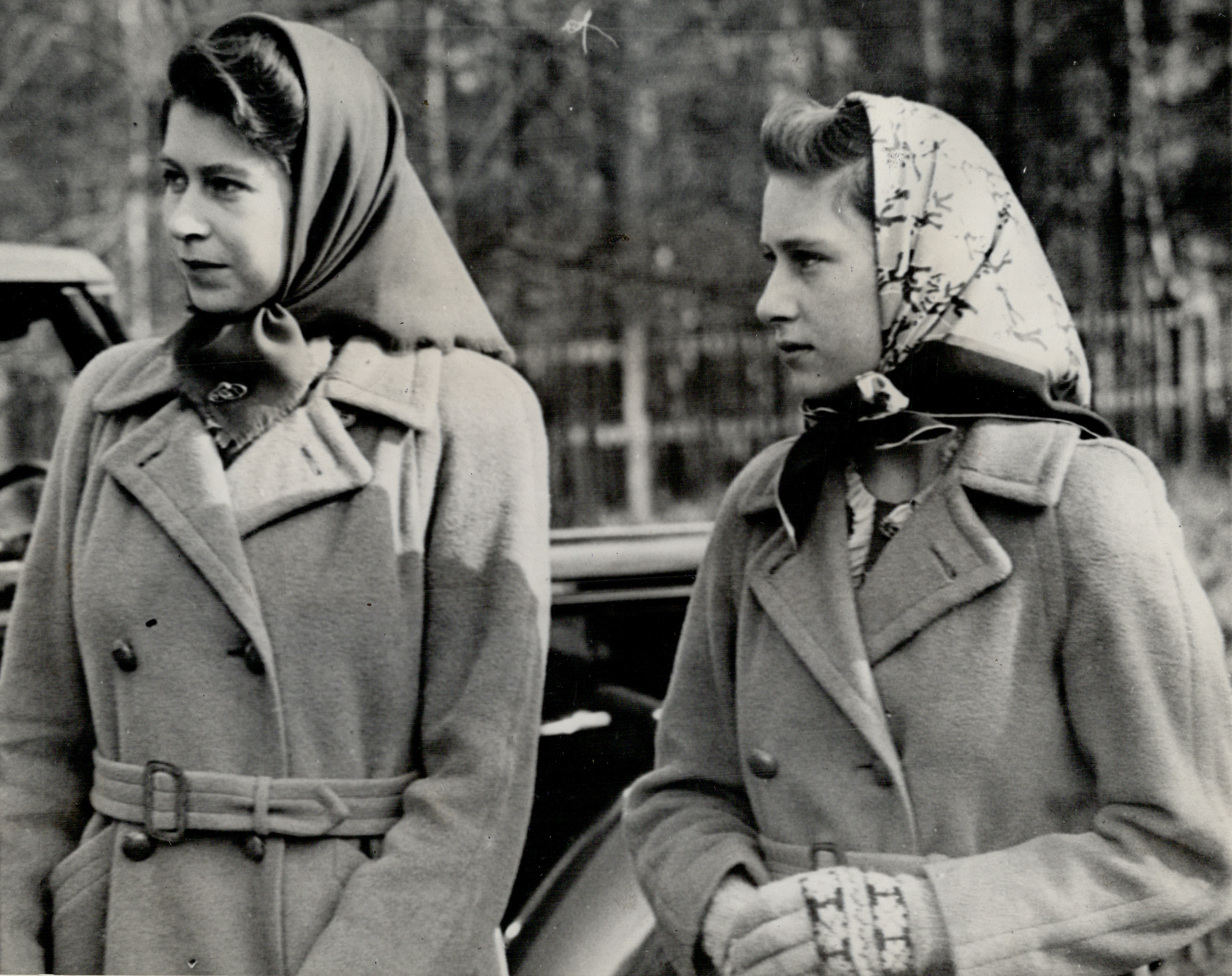 An old photo of a young Elizabeth and Margaret wearing kerchiefs on their heads and coats