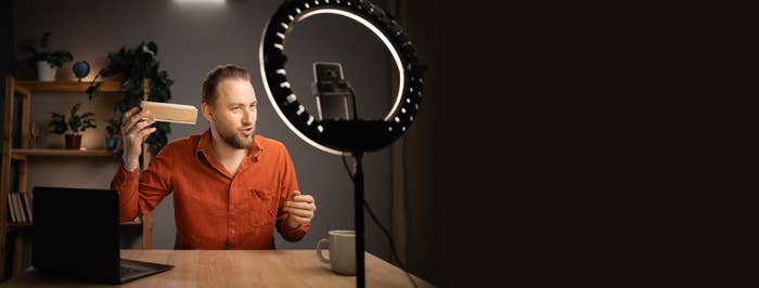 A man recording a video under a ring light