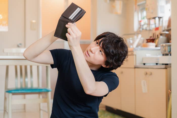 Young man holding an empty wallet above his head