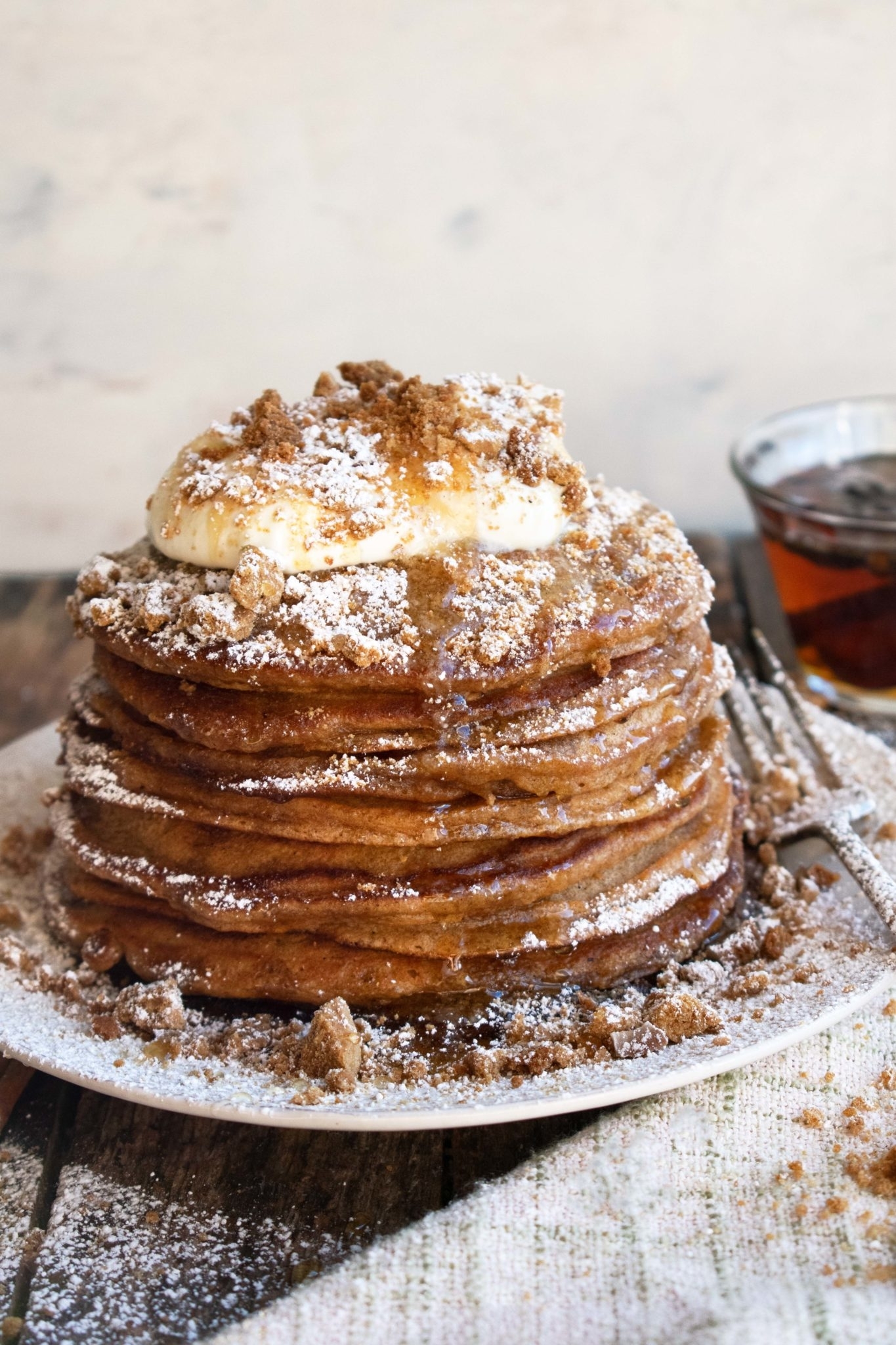 a stack of gingerbread pancakes dusted with powdered sugar and topped with whipped cream