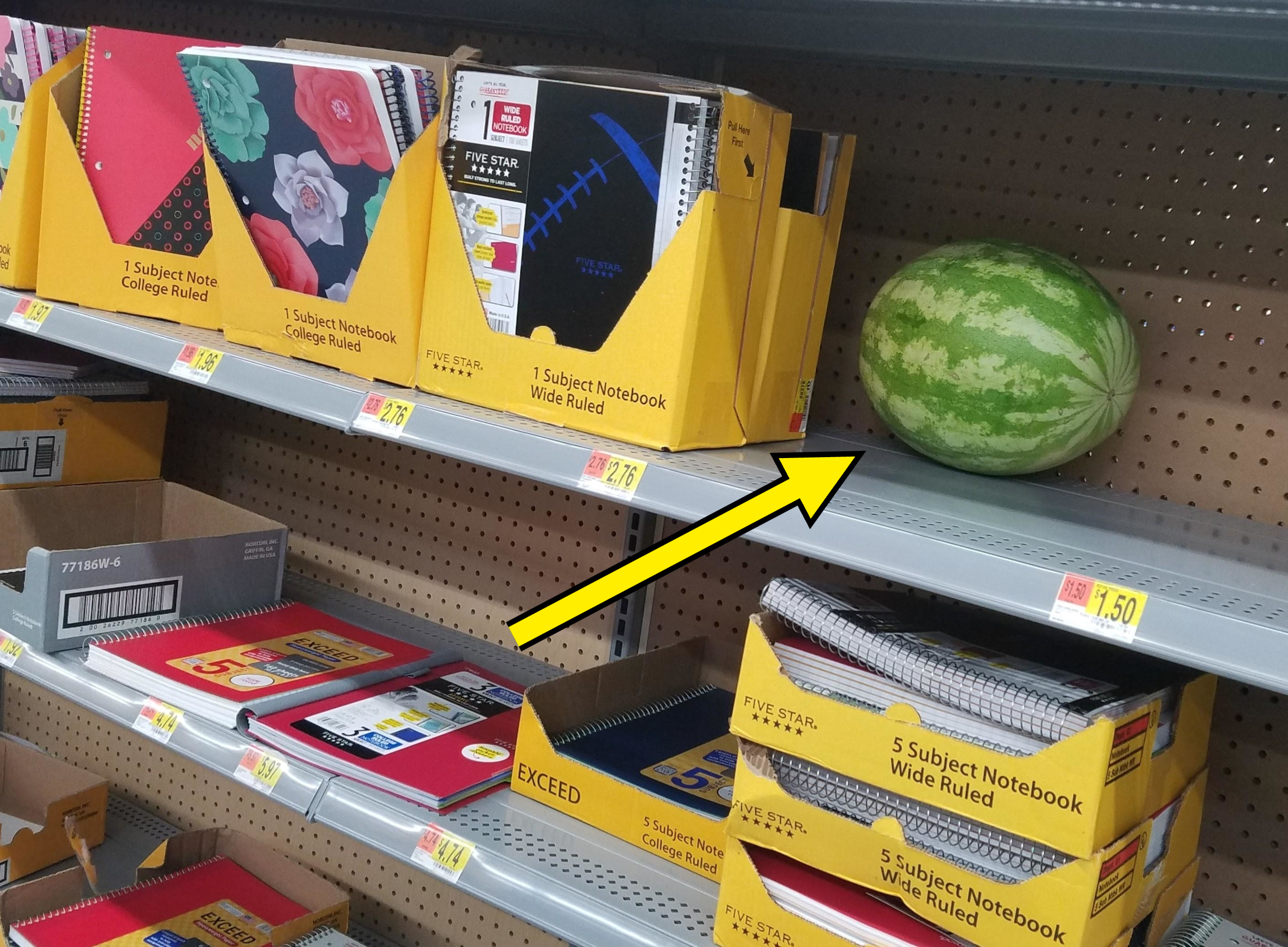 A watermelon on a shelf of school supplies