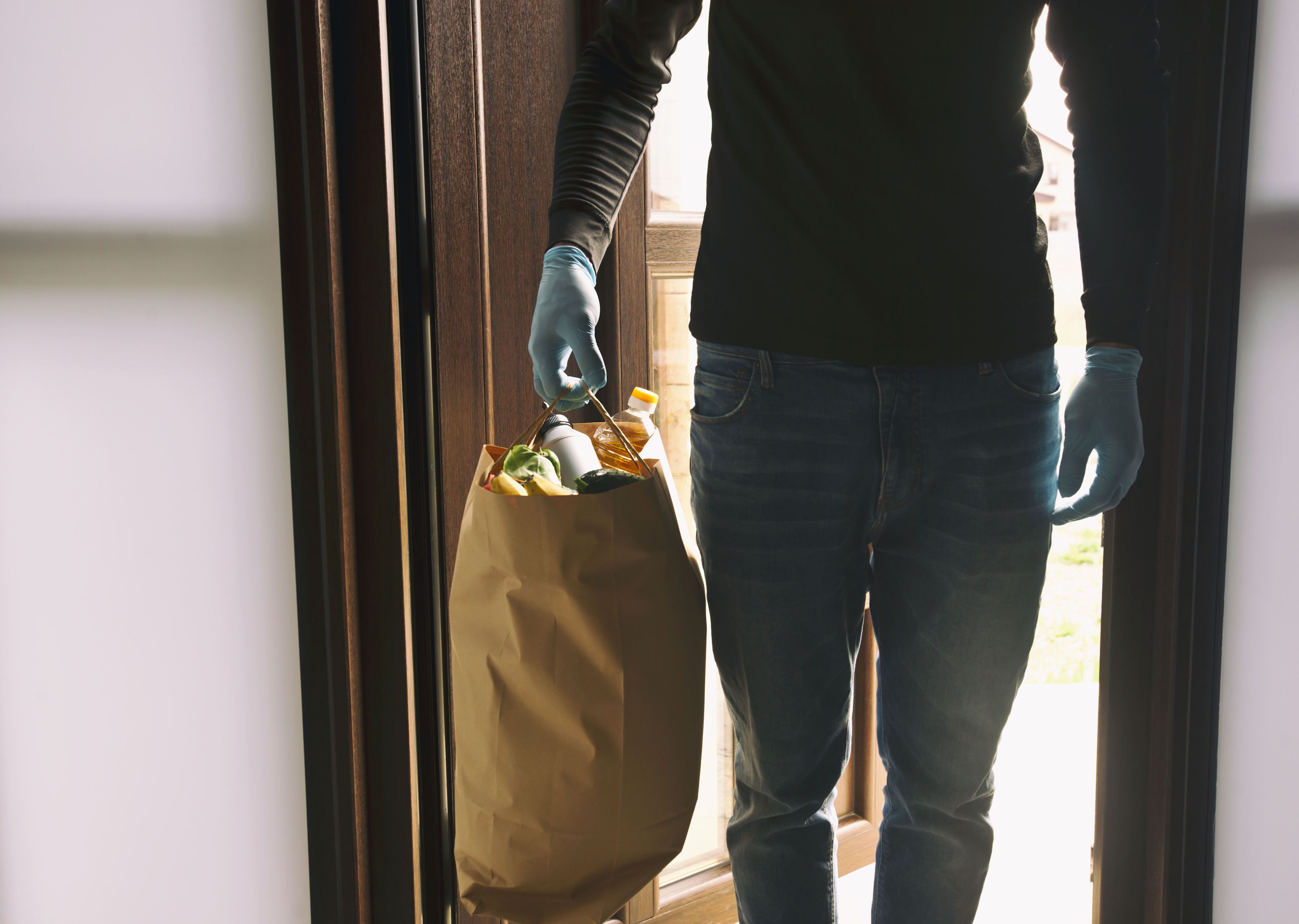 man wearing gloves with groceries in his hand