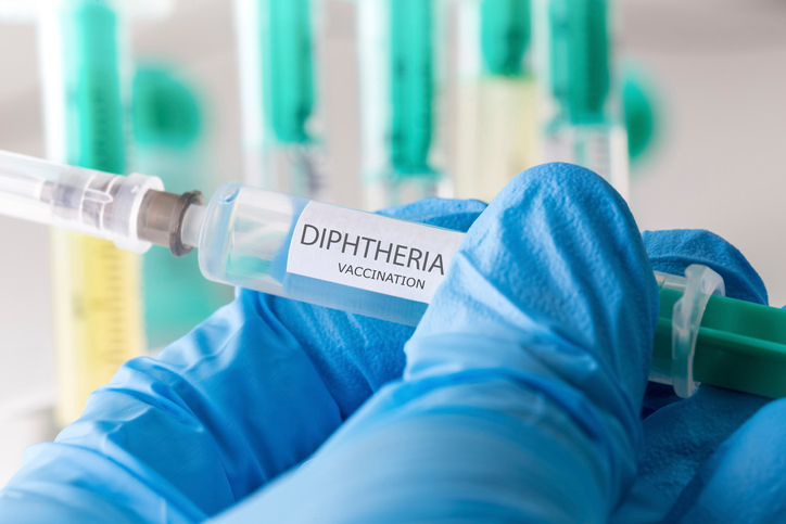 A doctor holding a syringe that says &quot;Dipththeria&quot;