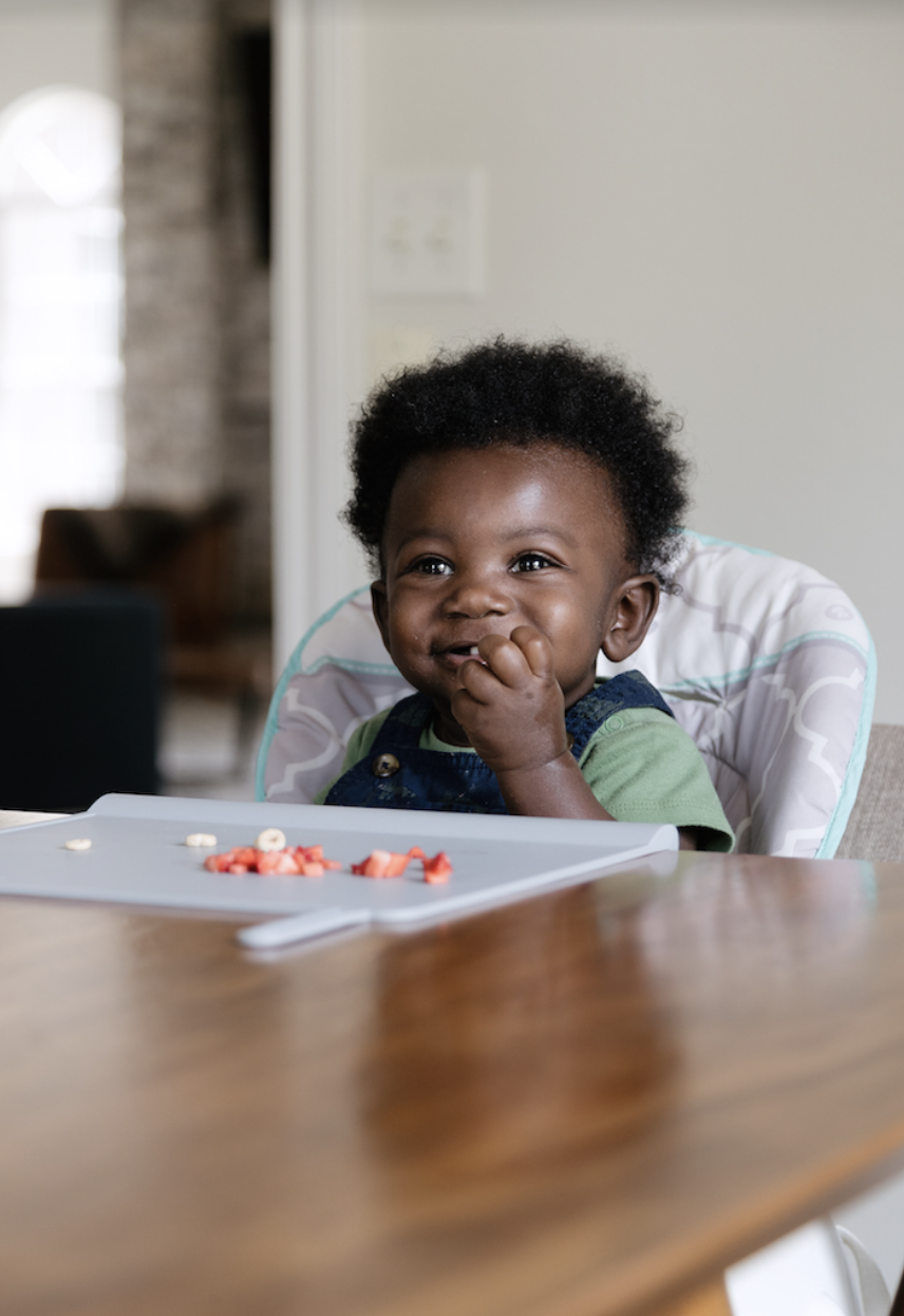 A baby eating snacks on a placemat.