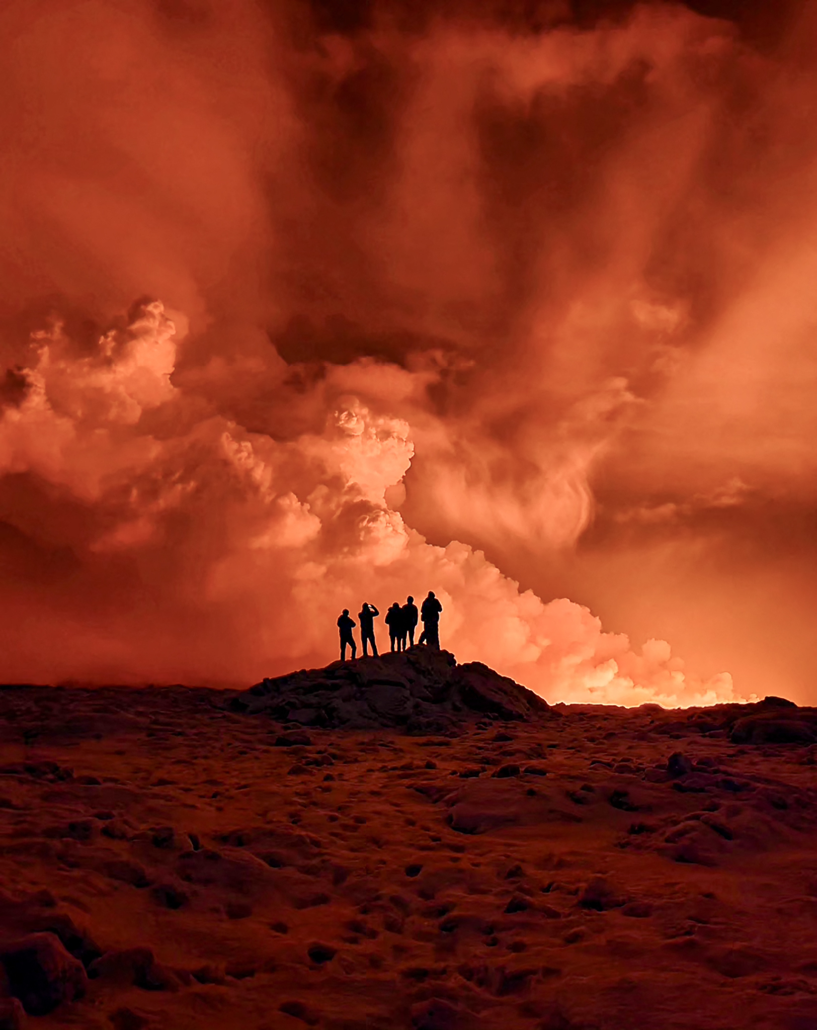 Silhouettes of people against the volcanic smoke
