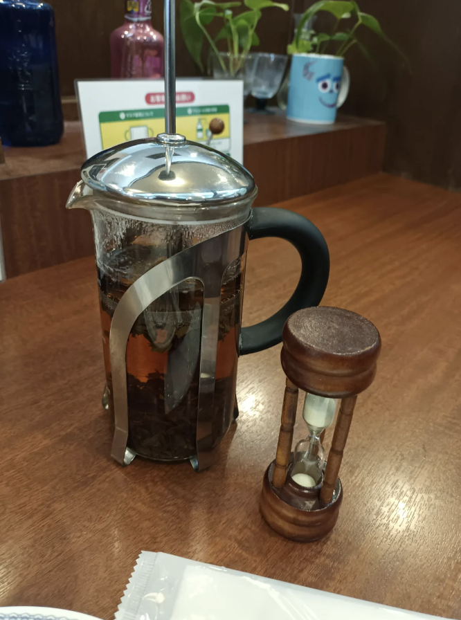 an hour glass next to a French press