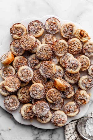 baked maple walnut tassies on a plate dusted with powdered sugar