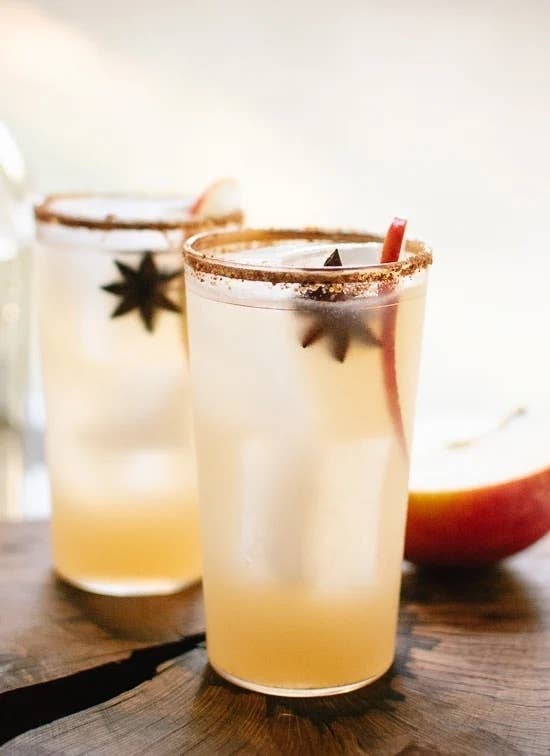 two glasses of spiced apple margaritas garnished with an apple slice and star anise pod