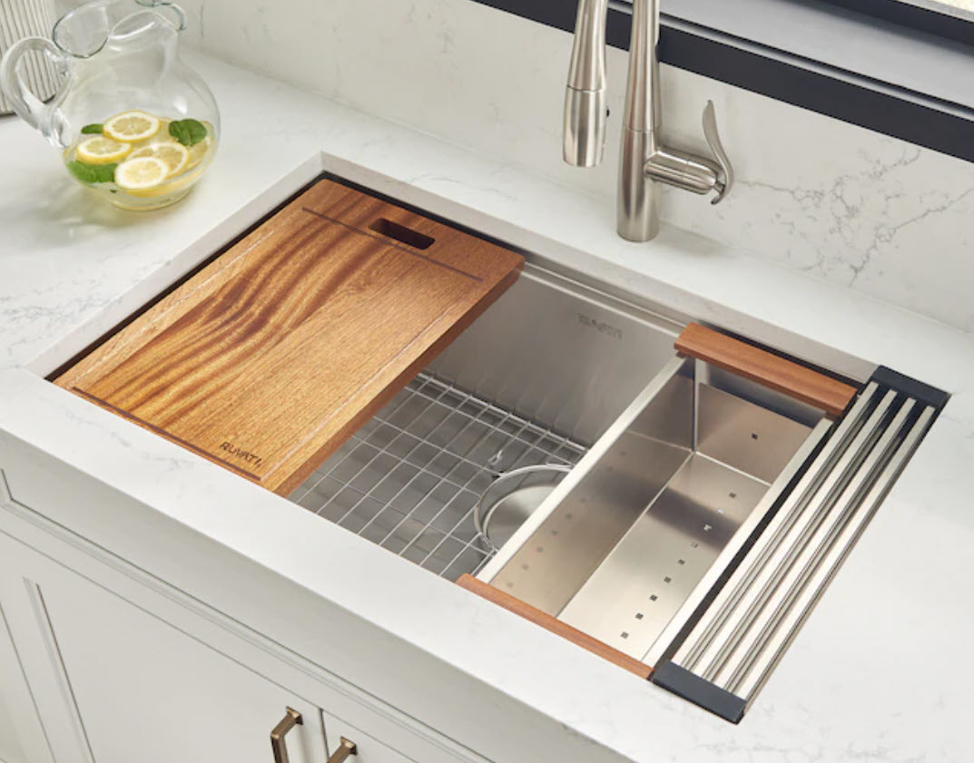 stainless steel farmhouse kitchen sink with wooden cutting board on top