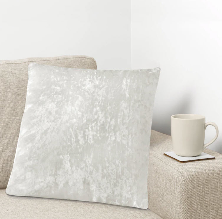 white soft velvet throw pillow on couch next to mug of coffee