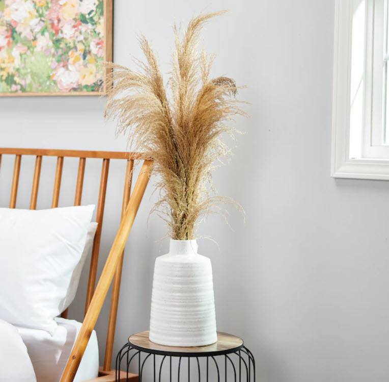 faux pampas inside white vase on side table
