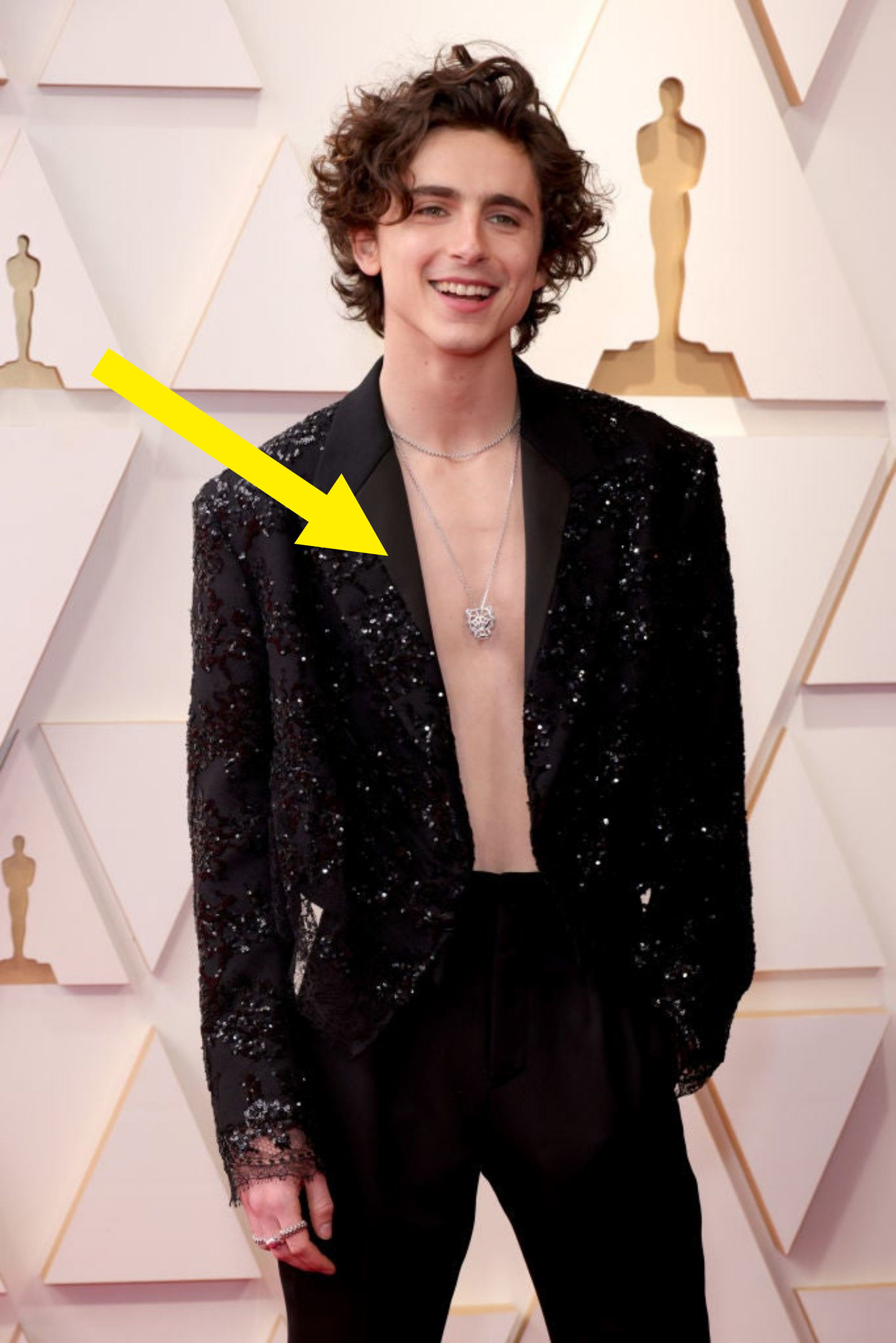 Closeup of him with no shirt under a sparkling blazer