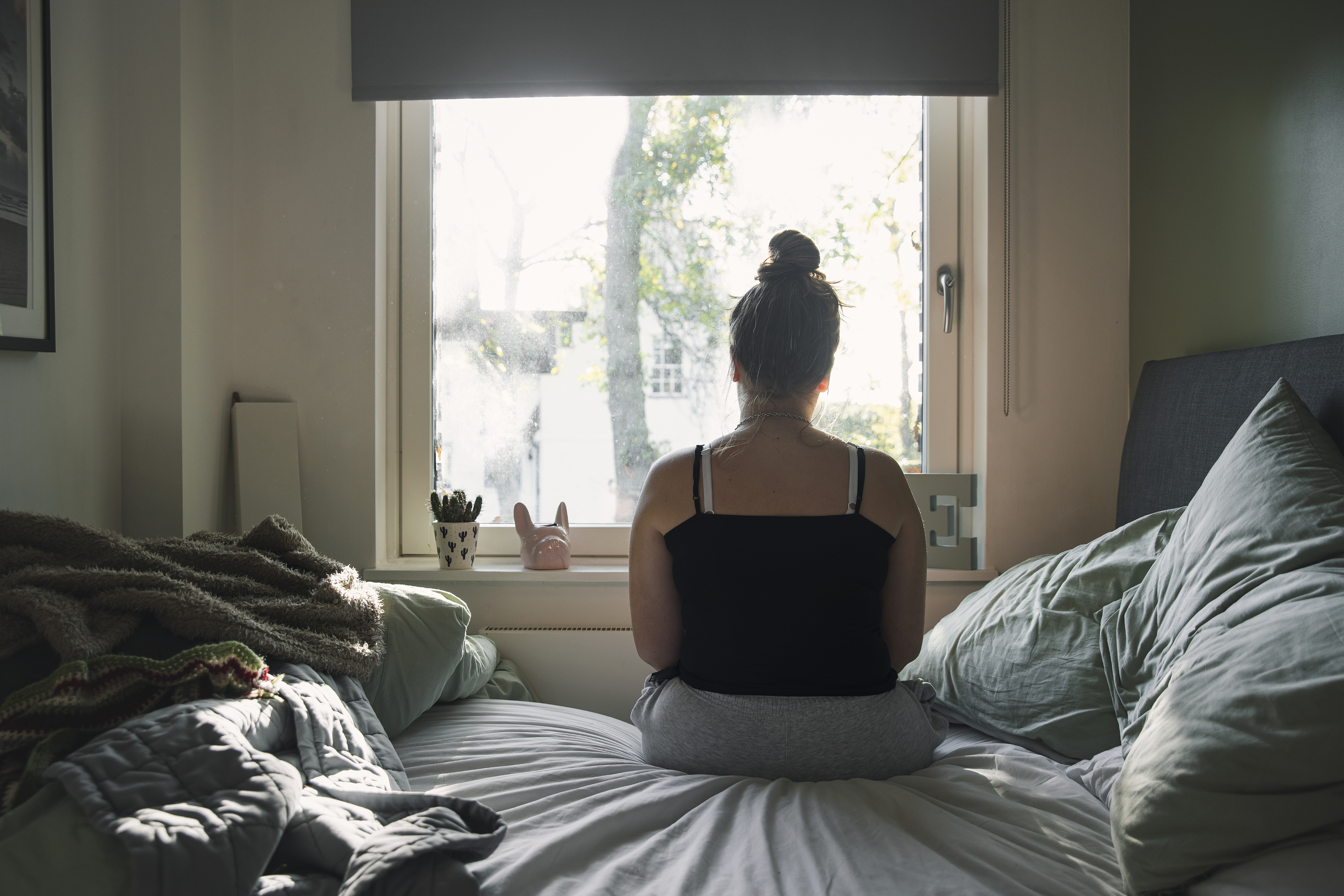 a person sitting on the bed looking out the window