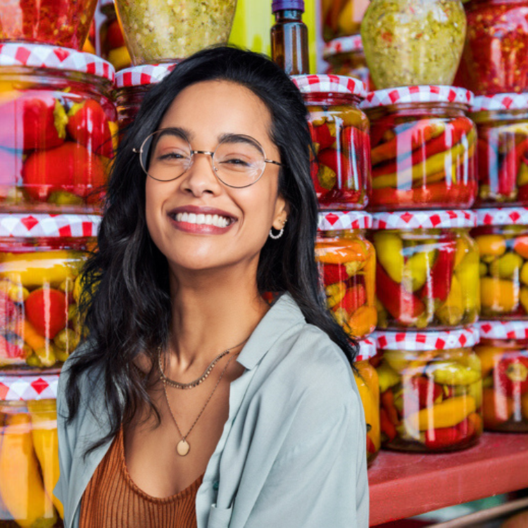 a woman standing in front of jars of pickles