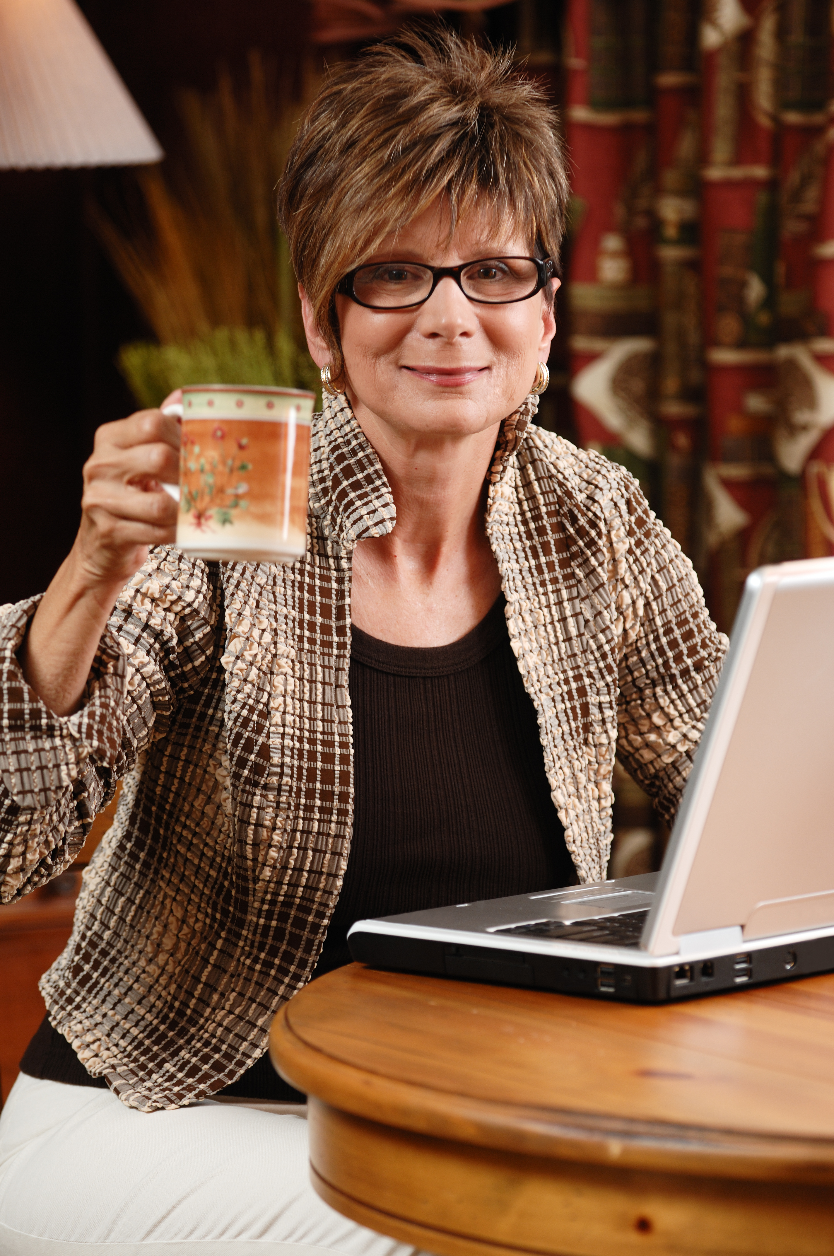 person at their laptop with their mug raised