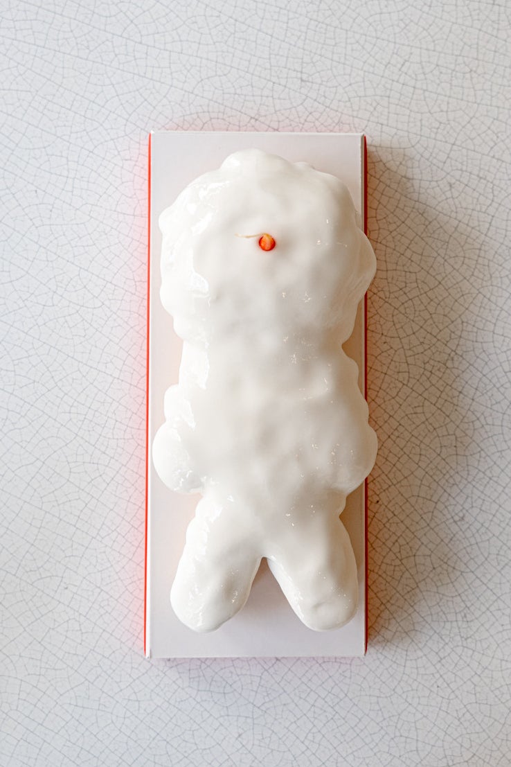 a white snowman shaped yule log with a candied carrot nose