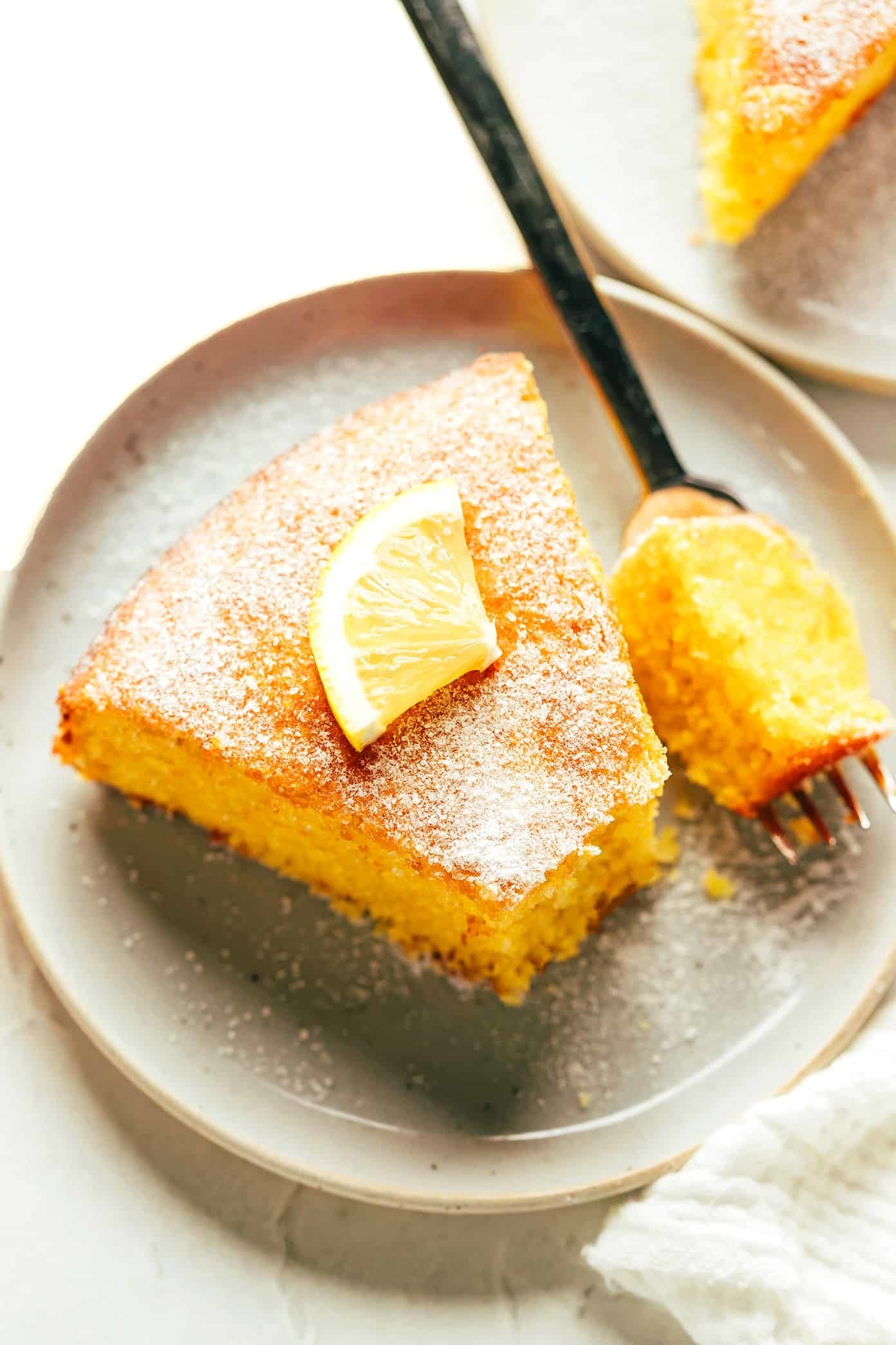 a slice of citrus olive oil cake dusted with sugar and topped with a lemon slice