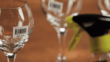 a gif of the product sprayed on sticky labels attached to wine glasses, which then melt off
