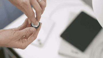 a gif showing a person peeling off the adhesive covering and sticking the clip onto a table, then using it to secure a charging cable in place