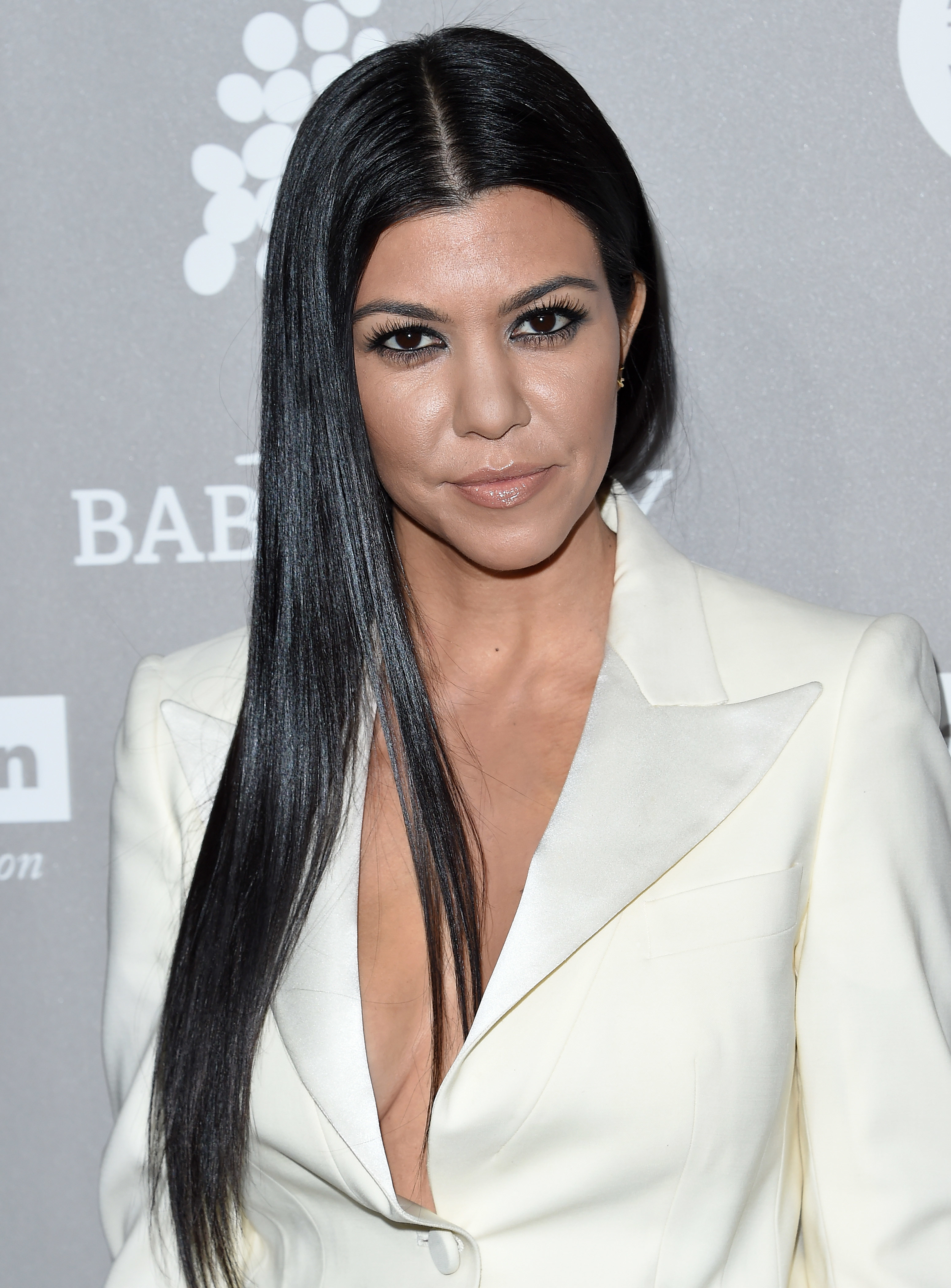 Close-up of Kourtney at a media event wearing a suit jacket