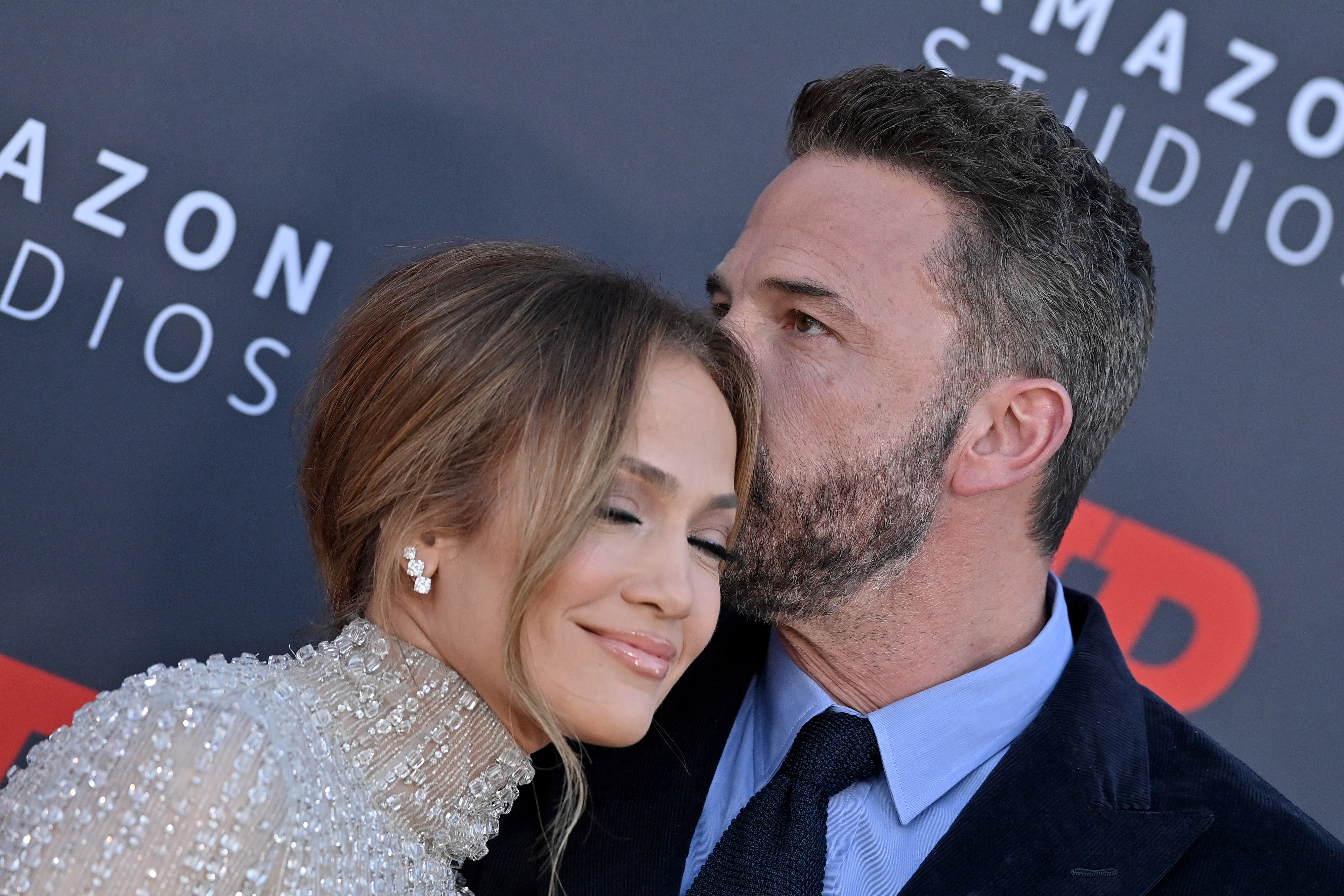 Close-up of JLo smiling and Ben kissing her hair  at a media event