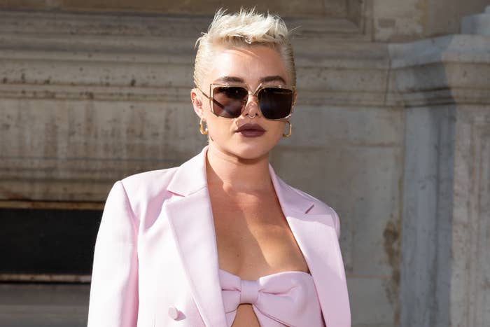 Close-up of Florence in sunglasses, spiked hair, and a suit jacket with a crop bow top