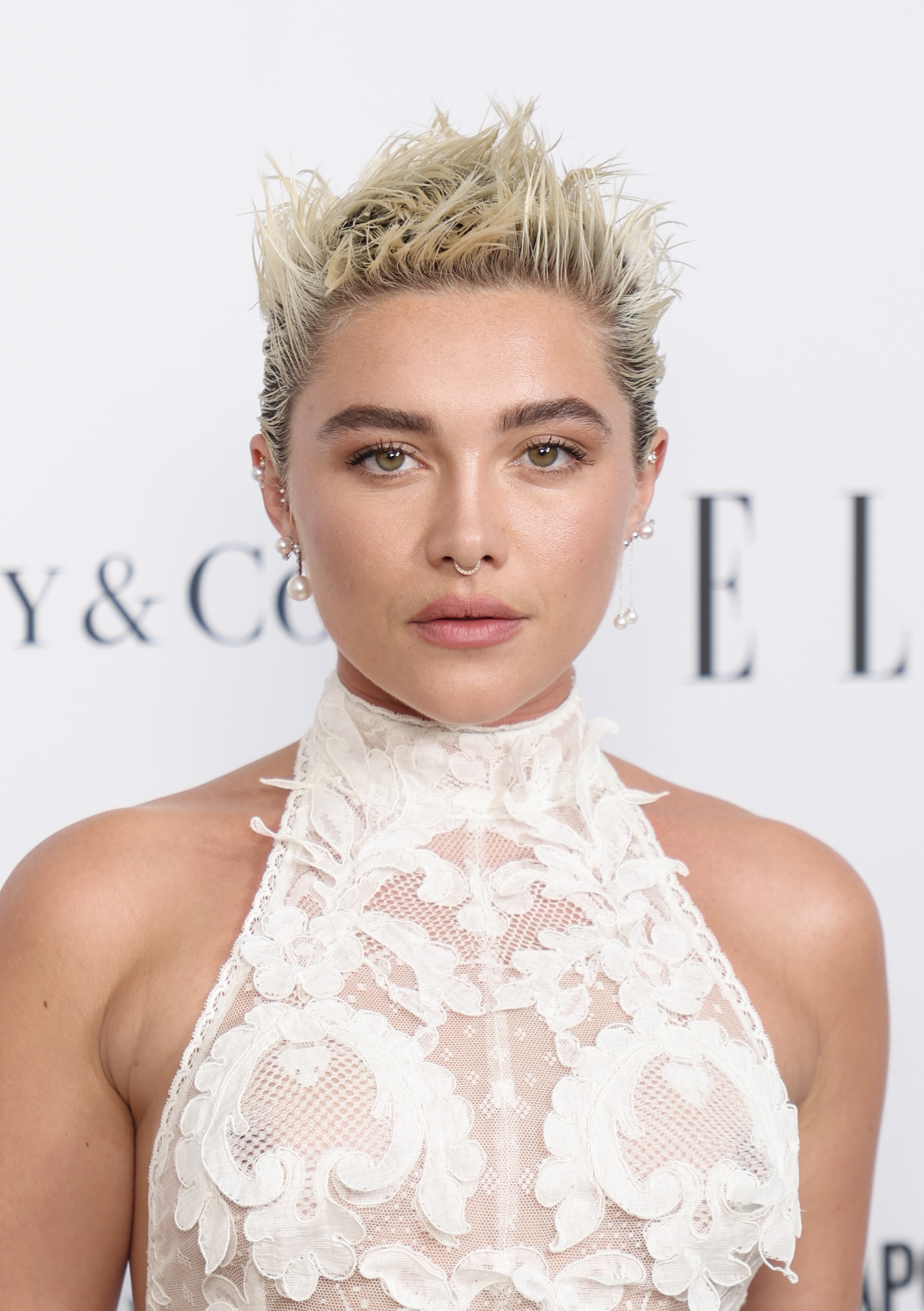 Close-up of Florence with spiked hair and wearing a lacy, sheer halter-top outfit at a media event