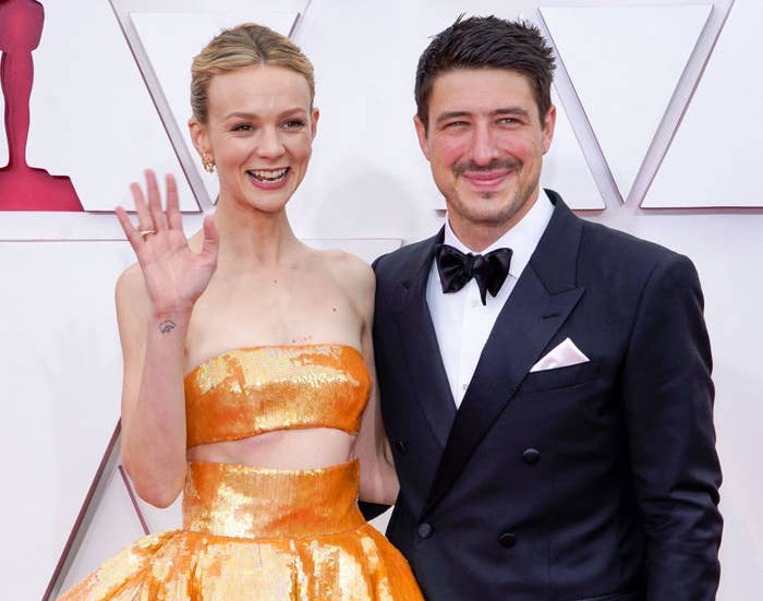 Closeup of Carey Mulligan waving on the red carpet with and Marcus Mumford