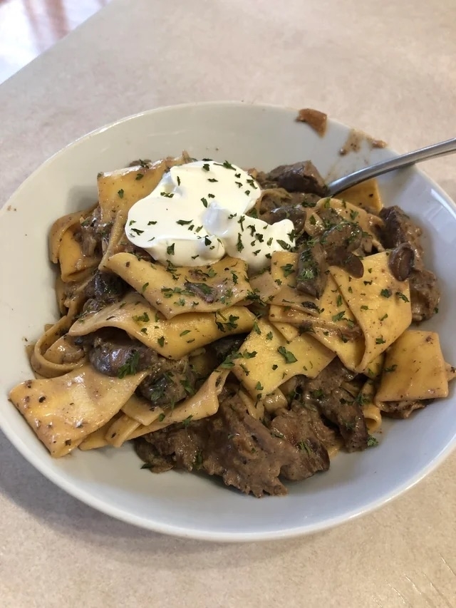 a plate of beef stroganoff topped with sour cream