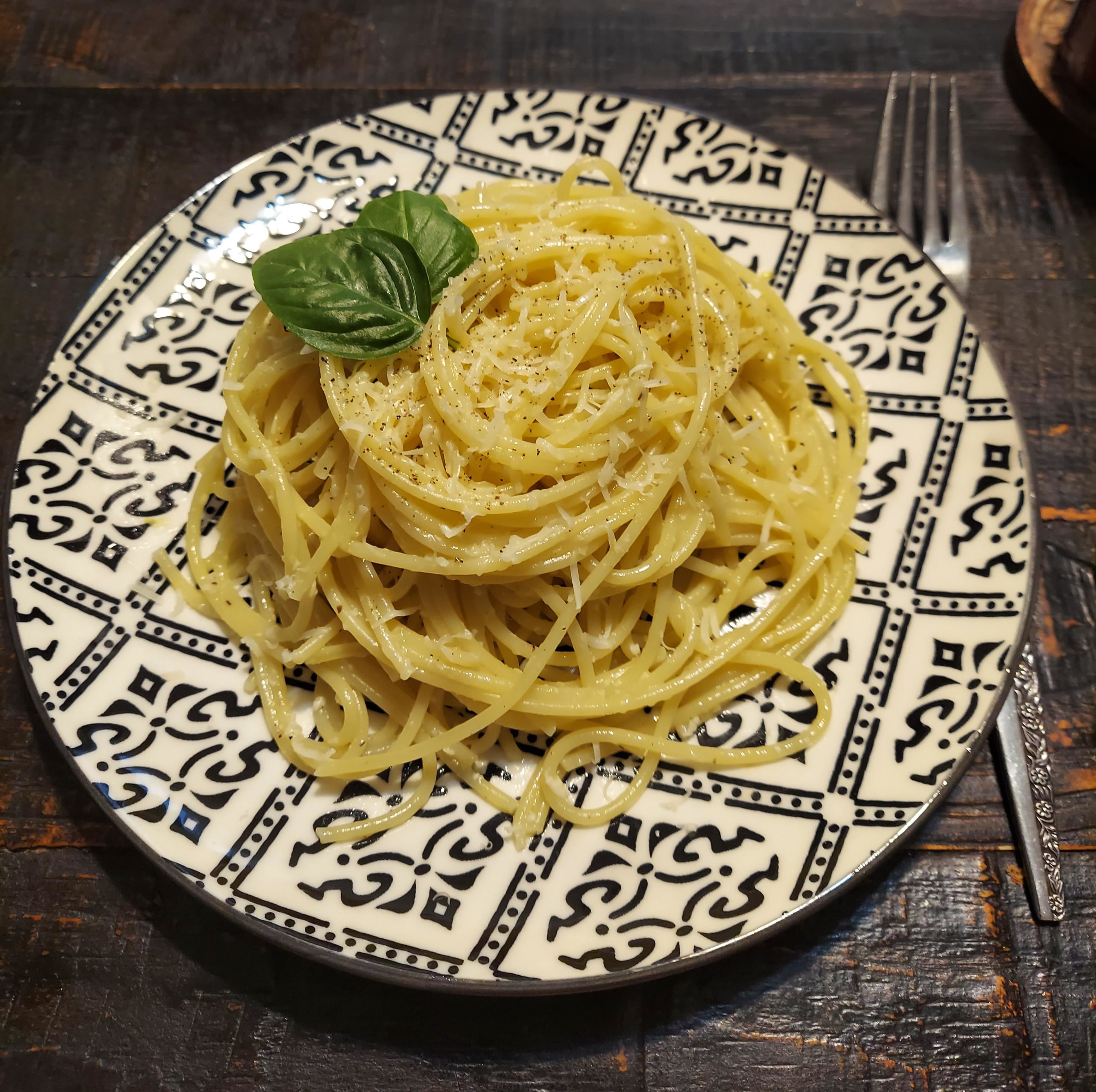a plate of lemon spaghetti topped with shredded parmesan cheese and basil