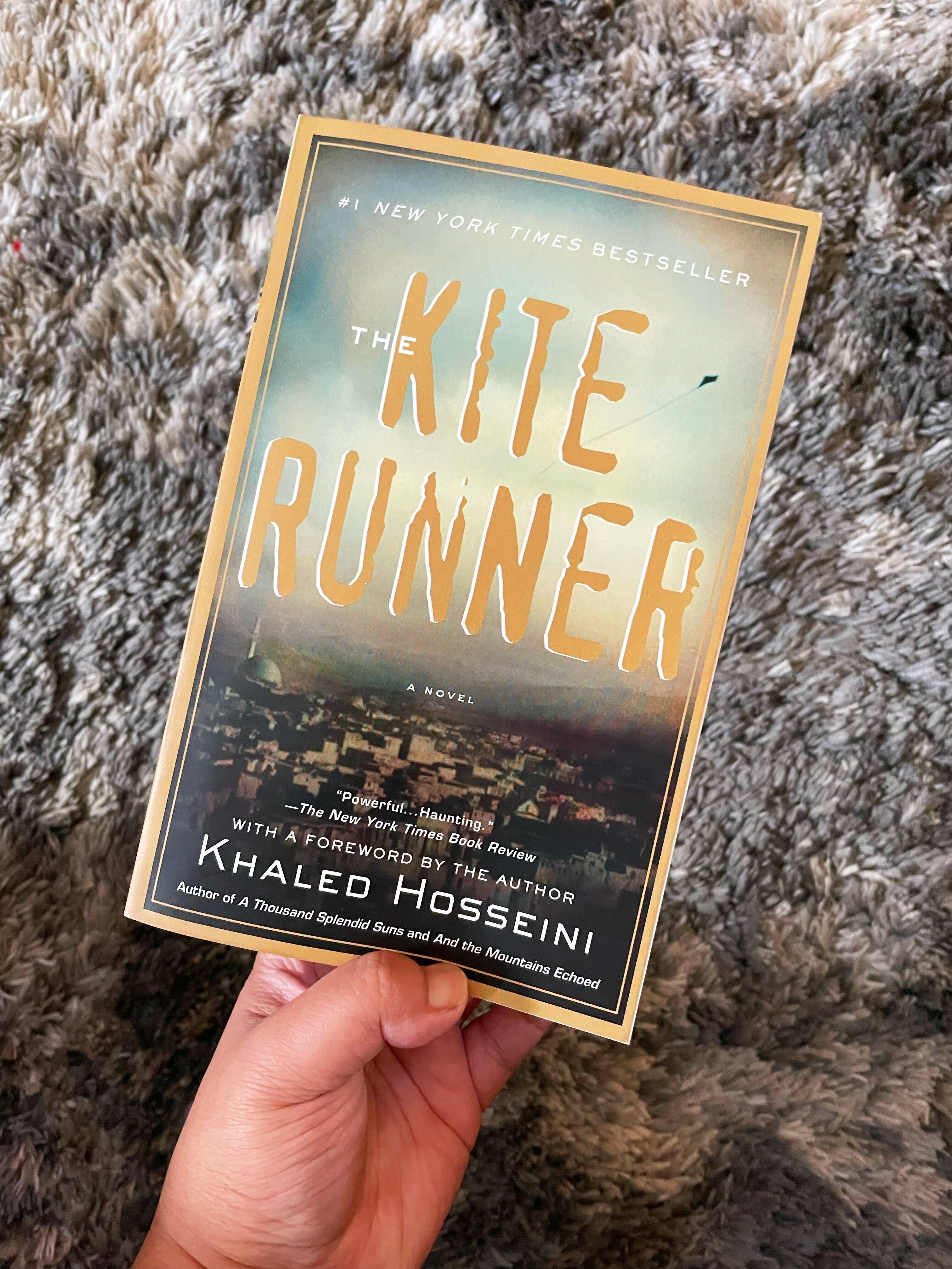 The author is holding a copy of Khaled Hosseini&#x27;s &quot;The Kite Runner&quot;