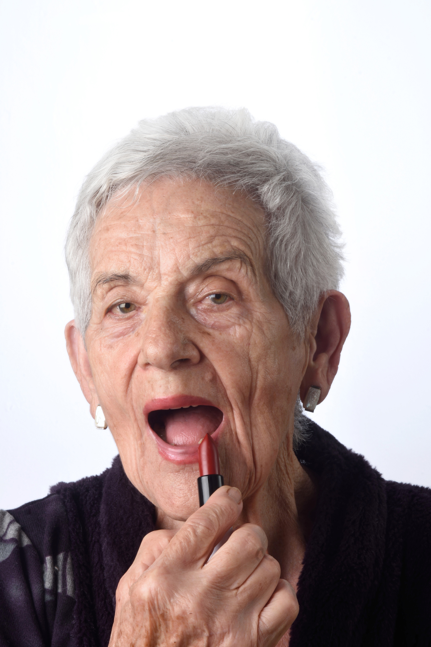 Close-up of an older woman applying lipstick