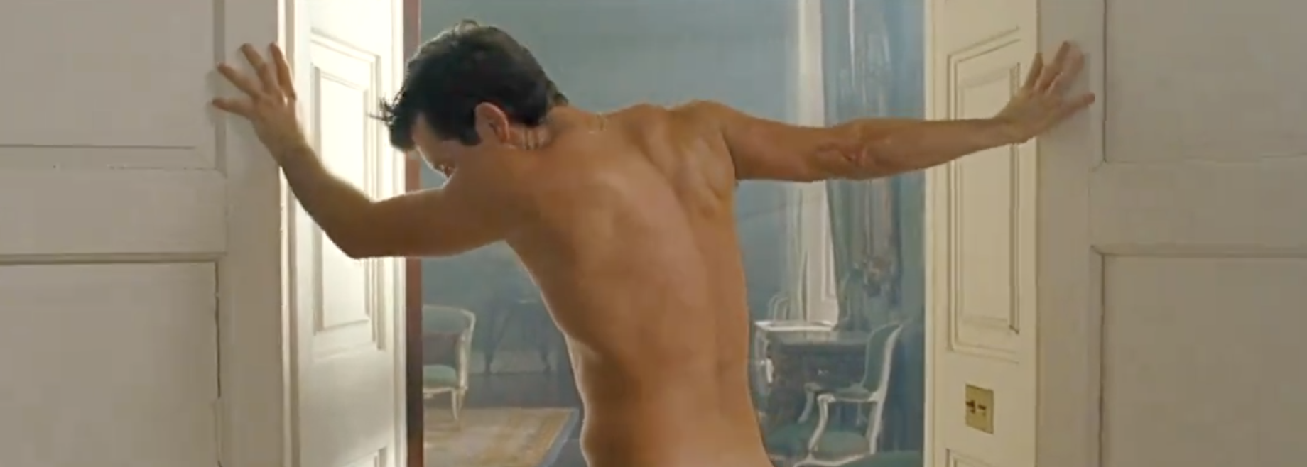 Barry seen naked from the waist up from the back, standing in a doorway