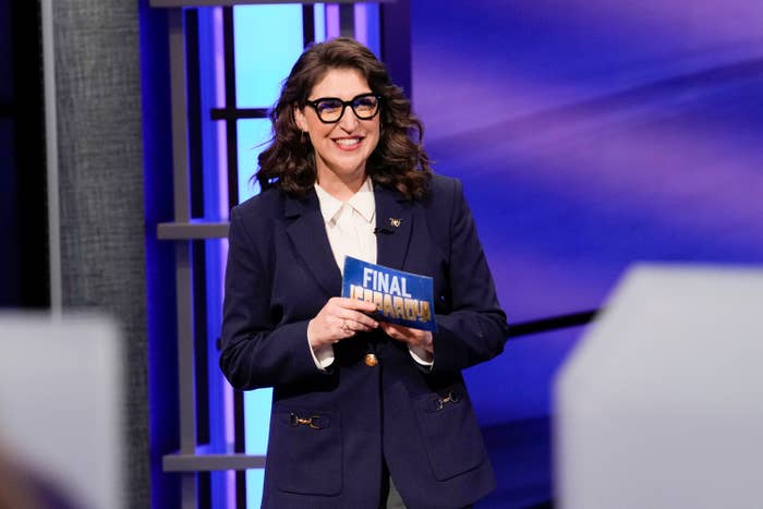 Mayim on Jeopardy smiling and holding a Final Jeopardy card