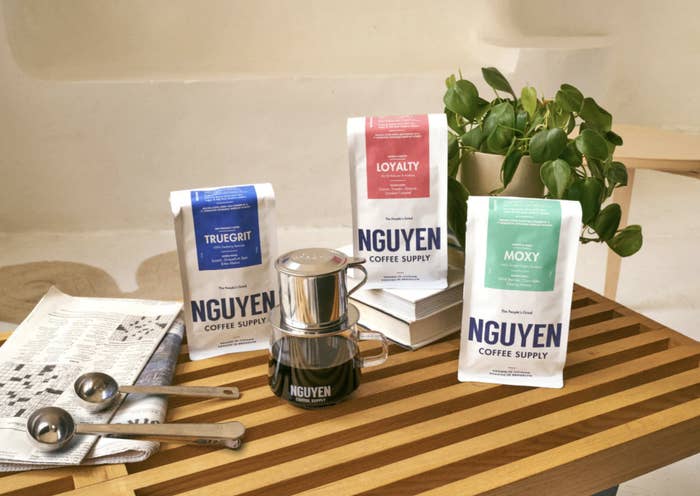 Nguyen Coffee Supply coffee bags next to phin filter and measure spoons