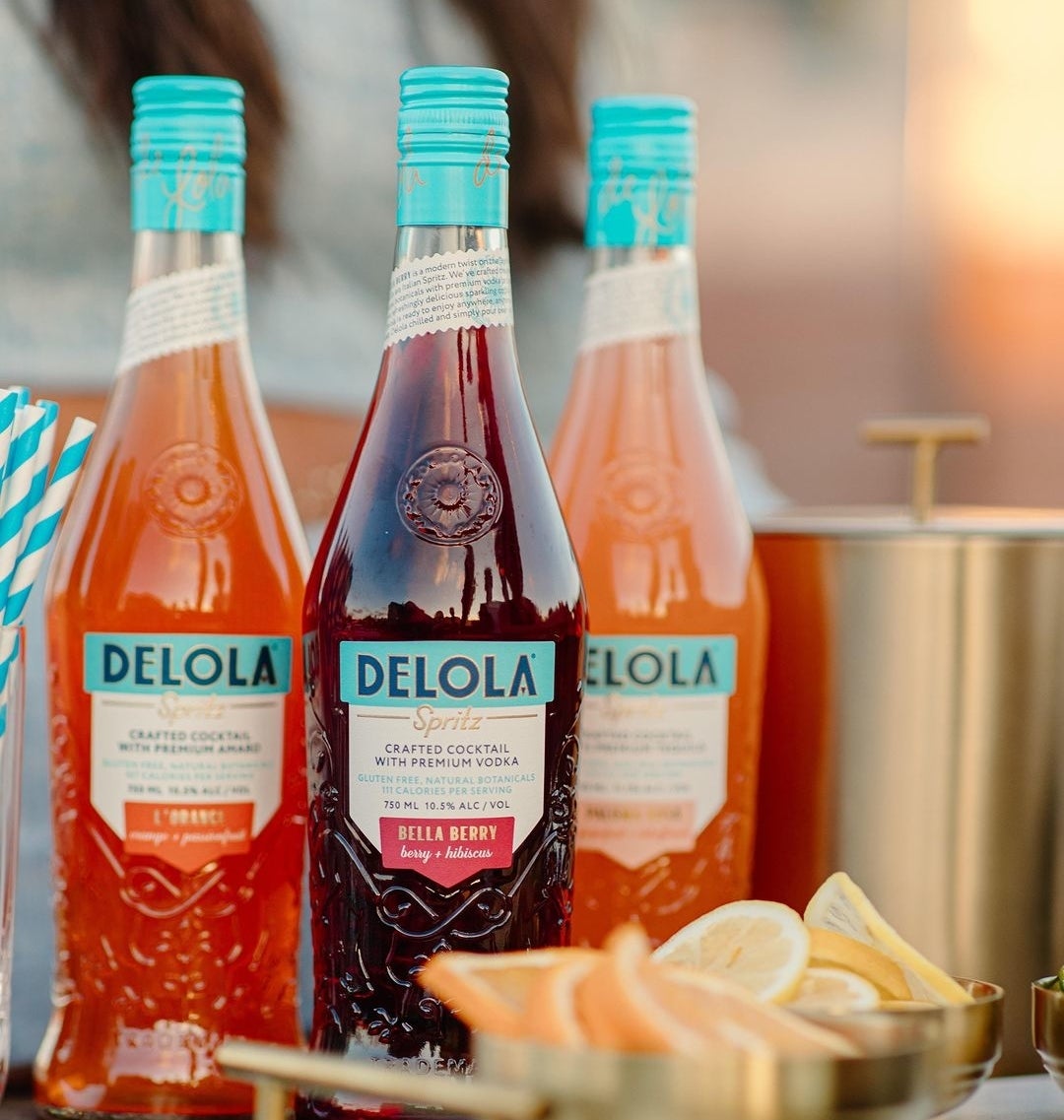 Three bottles of Delola next to bartending ingredients.