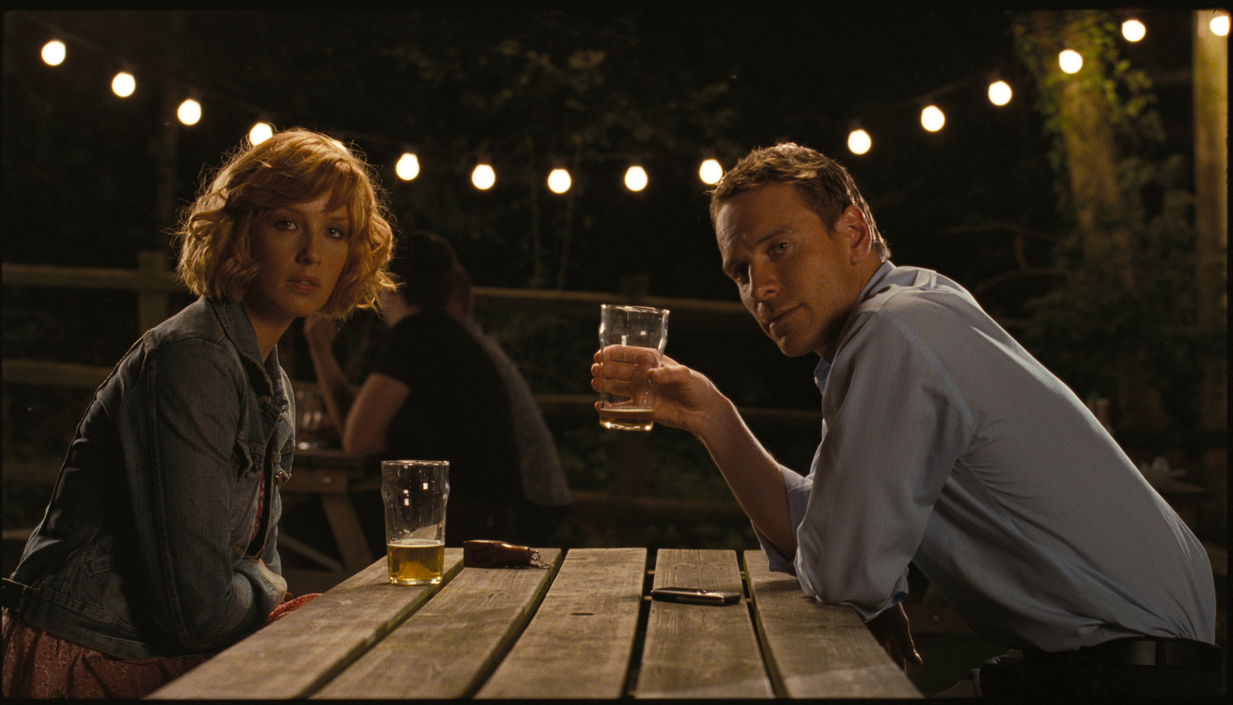 Kelly Reilly and Michael Fassbender drinking beers.